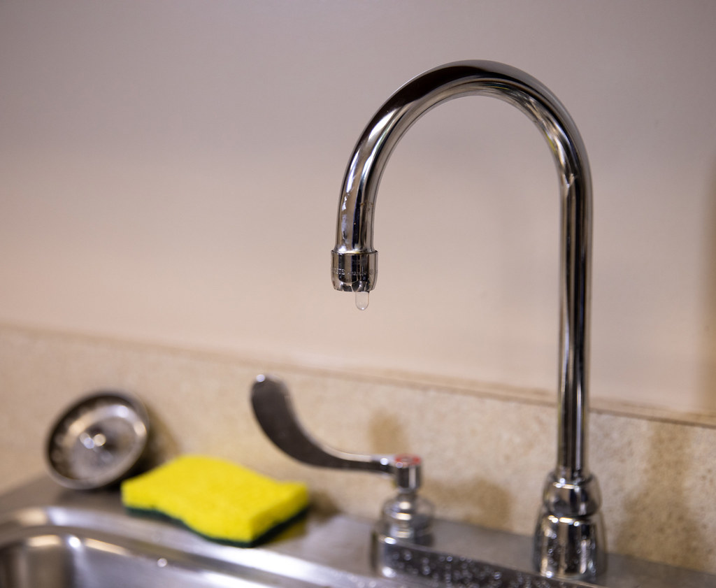 Chrome kitchen faucet with a single drip of water at the spout