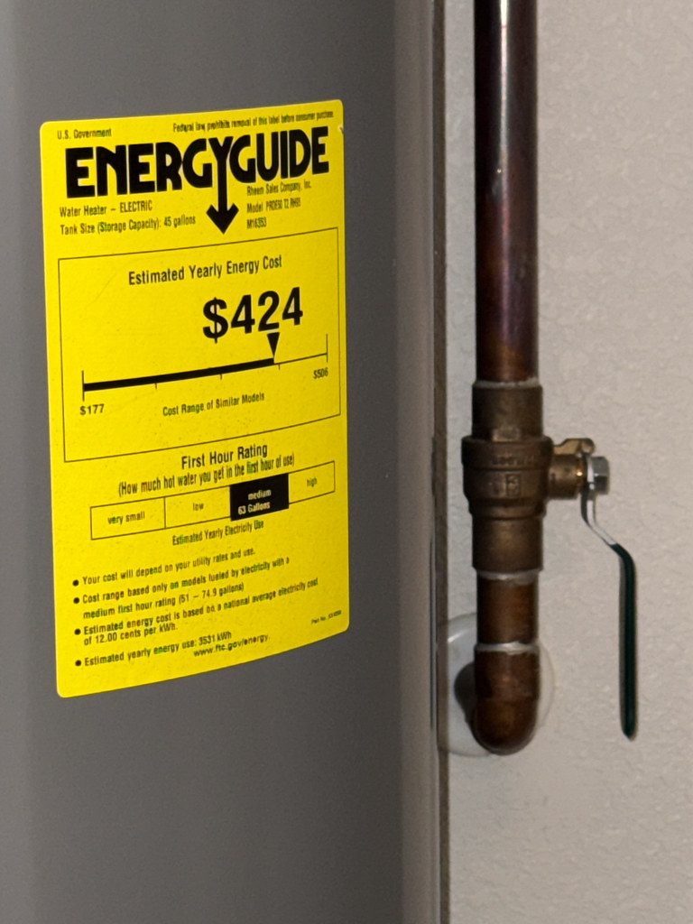 Electric tank water heater with EnergyGuide label and copper supply line